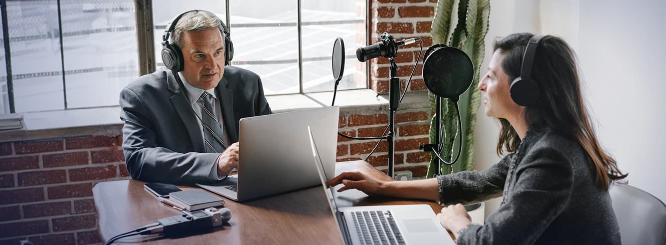 A voice actor recording dialogue in a professional soundproof studio booth with a microphone and script.